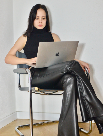 woman sitting on chair wearing a sleeveless top and flared faux leather pants