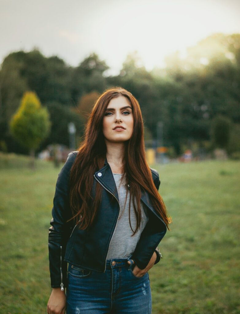 young woman wearing a stylish black motorcycle jacket with blue jeans