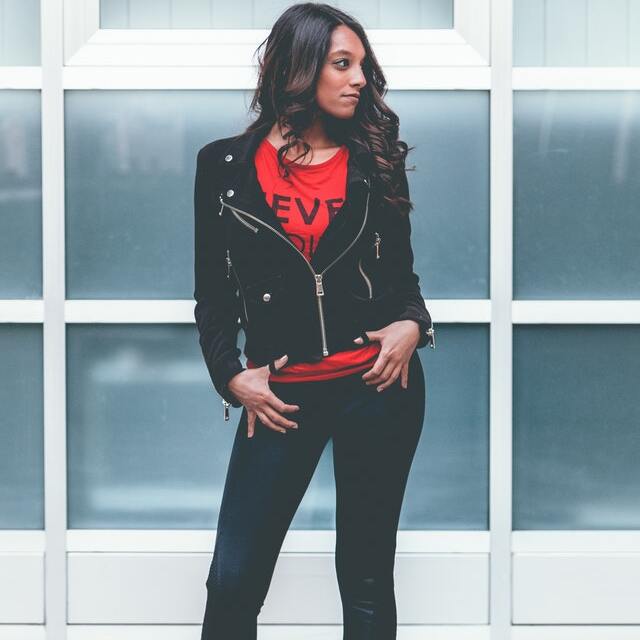 woman wearing cropped biker jacket and red top with black jeans