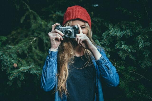 girl with a camera wearing a denim jacket and beanie