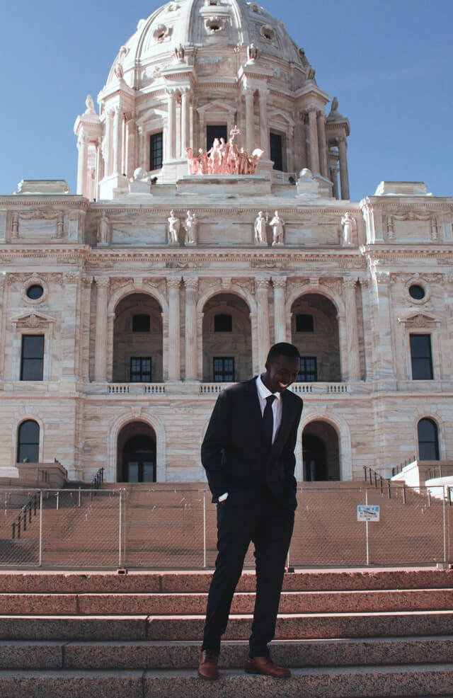 man wearing a black suit and brown leather shoes